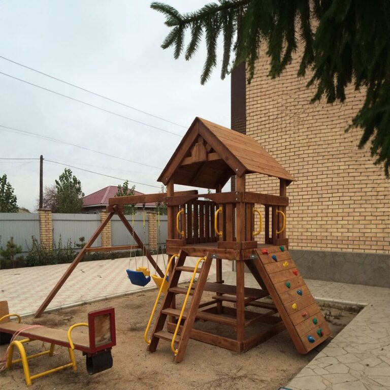 Небольшая детская игровая площадка из натурального дерева во дворе частного дома в Астане